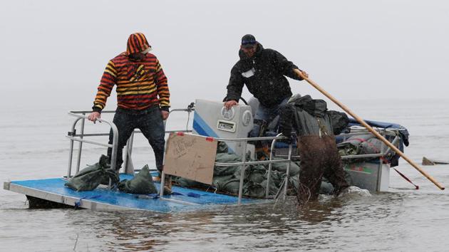 Men struggle with a pontoon boat loaded with sandbags. Across eastern Canada, hundreds of thousands of sandbags have been used and Ottawa has asked suppliers for up to four million more, said officials. (Chris Wattie/REUTERS)