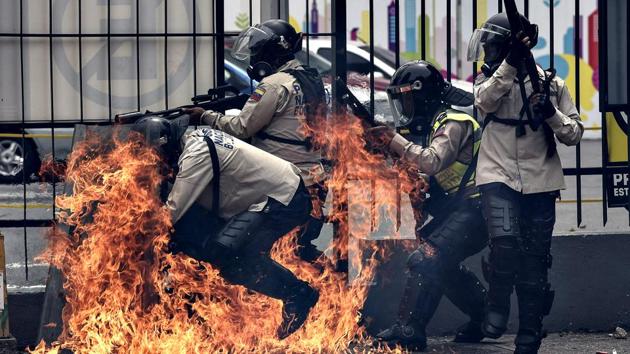 A group of riot policemen are hit by a Molotov cocktail hurled by an opposition demonstrator during a protest against President Nicolas Maduro, in Caracas . Since April 1, Venezuela has been experiencing a wave of demonstrations both for and against the government, some of which have turned violent, leaving many dead and hundreds injured. (CARLOS BECERRA / AFP)