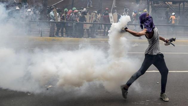 A demonstrator hurls back a tear gas canister at riot police during a protest against President Nicolas Maduro, in Caracas . Fresh street protests against President Nicolas Maduro's efforts to reform the constitution in a deadly political crisis. Supporters of the opposition Democratic Unity Roundtable (MUD) gathered in eastern Caracas to march to the education ministry under the slogan ‘No to the dictatorship.’ (JUAN BARRETO / AFP)