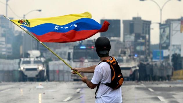 A Venezuelan opposition demonstrator waves a flag at the riot police in a clash during a protest . (FEDERICO PARRA / AFP)