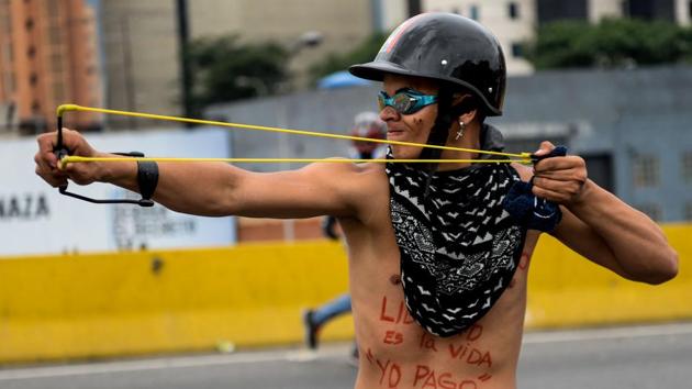 A Venezuelan opposition activist uses a slingshot in clashes with the riot police during a protest. (EDERICO PARRA / AFP)