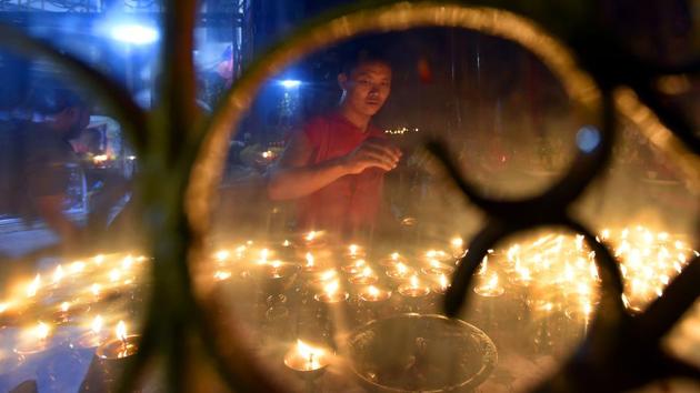 Monks light candles and pray to Buddha statue  at Majnu Ka teela in New Delhi. (Raj K Raj/HT PHOTO) 