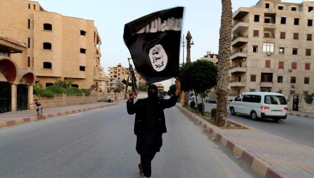 An Islamic State supporter walks down a street waving the terror organisation’s dreaded white-on-black flag.(Reuters/ File photo)