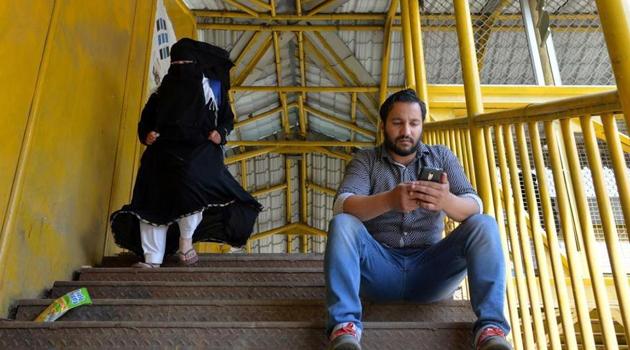 A Kashmiri man browses the internet on his mobile phone on a footbridge in Srinagar. A statement released and published by the UN high commissioner for human rights said the social media gag was a “collective punishment” that didn’t meet the international standards for limiting free speech.(AFP file)