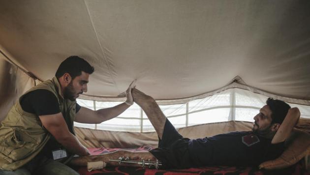 In this Monday, May 8, 2017 photo, Rayan Salah Mohammed (33) receives physiotherapy from Mohammed inside his tent in the Hasan Shamp camp in Northern Iraq. Rayan lost his leg after a mortar hit their house in Eastern Mosul.(AP Photo)