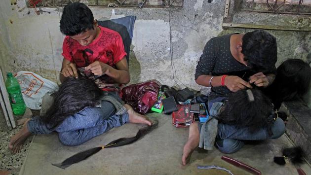 Here, two labourers knot the hair into the wig base or ‘cap’. Each cap is made to fit a specific person’s head, using monofilament net imported from Korea (Satyabrata Tripathy /HT Photo)