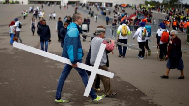 On the day before the arrival of Pope Francis, a pilgrim carries a cross at the Catholic shrine of Fatima. One of these apparently took place in 2013, when a five-year-old Brazilian boy called Lucas recovered at lightning speed after falling more than six metres (20 feet) down to the ground from a window, smashing his skull. (Rafael Marchante/reuters)