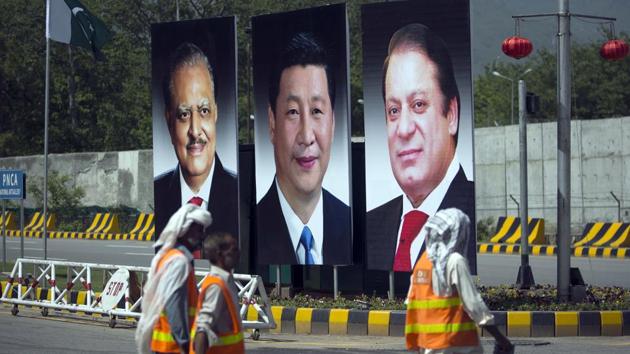 In this April 20, 2015 file photo, municipality workers walk past a billboard showing pictures of Chinese President Xi Jinping, center, with Pakistan’s President Mamnoon Hussain, left, and Prime Minister Nawaz Sharif on display during a two-day visit by the Chinese president to launch an ambitious $45 billion economic corridor linking Pakistan’s port city of Gwadar with western China, in Islamabad, Pakistan.(AP Photo)