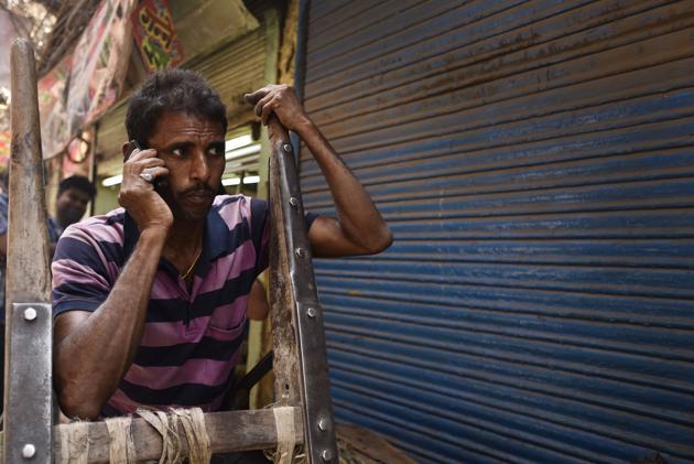 Prem, a labourer from Rajasthan takes a break while talking on phone. (Burhaan Kinu/HT PHOTO)