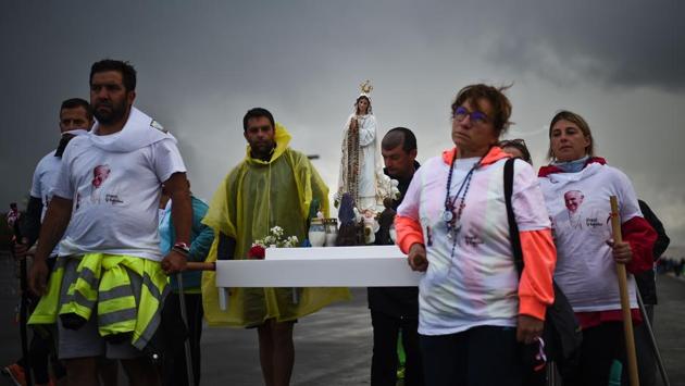Pilgrims wearing t-shirts with the picture of Pope Francis carry the image of Our Lady of Fatima upon their arrival at Fatima Sanctuary. She apparently shared three major prophesies with the trio at a time marked by the ravages of the First World War and Church persecution in a relatively new Portuguese republic. (Patricia De Melo Moreira/AFP)