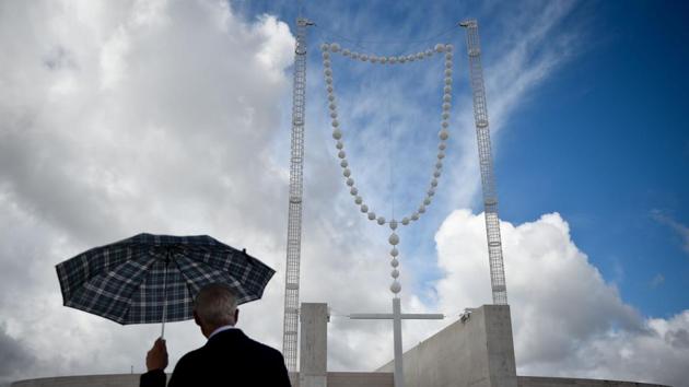 A man holding an umbrella looks at a big rosary at Fatima Sanctuary. (Patricia De Melo Moreira/AFP)