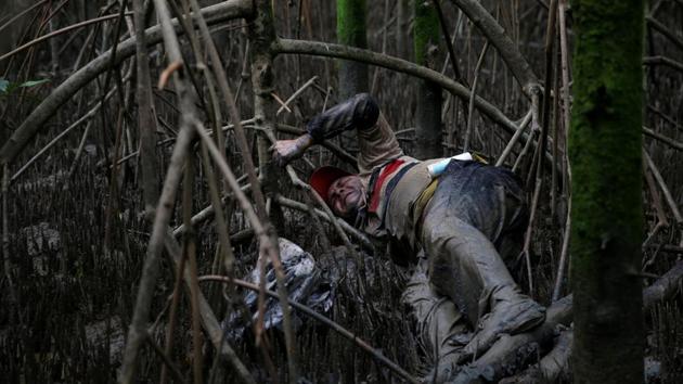 Jailson, a crab collector, tries to pick a crab at a mangrove swamp. (Ricardo Moraes/REUTERS)