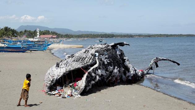 A boy looks at a whale shaped art installation that is made of plastic and trash made by environmental activist group Greenpeace Philippines, lying along the shore in Naic, Cavite, in the Philippines. (Erik De Castro / REUTERS)