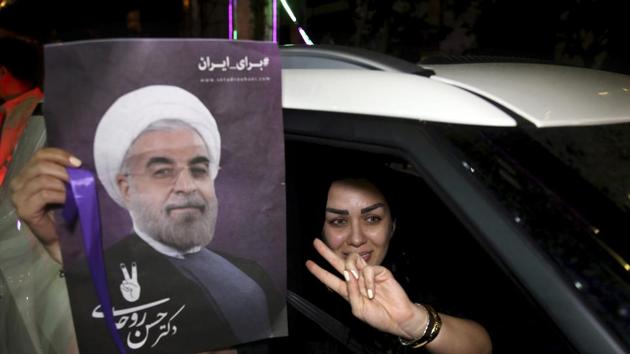 A supporter of Iran's President Hassan Rouhani, who is running for a second term in office, makes a V sign as she holds a poster of Rouhani in a car in Tehran, Iran, Friday, May 12, 2017.(AP Photo) A supporter of Iran's President Hassan Rouhani, who is running for a second term in office, makes a V sign as she holds a poster of Rouhani in a car in Tehran, Iran, Friday, May 12, 2017.(AP Photo)