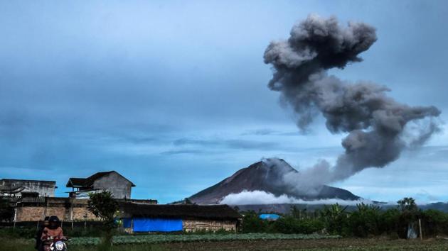Motorists ride along a road as Mount Sinabung volcano spews thick volcanic ash, as seen from Tangkulen village in Karo. Sinabung roared back to life in 2010 for the first time in 400 years. After another period of inactivity, it erupted once more in 2013 and has remained highly active since. (TIBTA PANGIN / AFP)