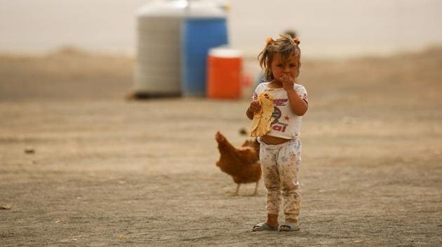 A displaced child, who fled from the Islamic State (IS) group bastion of Raqa, stands outside as she eats a loaf of bread in a camp for displaced near the town of al-Karamah, 26 kms from Raqa. (DELIL SOULEIMAN / AFP)