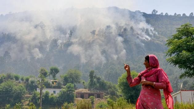 A lady points at smoke caused by firing of mortar shells from the Pakistan side of the border. A lady points at smoke caused by firing of mortar shells from the Pakistan side of the border.
