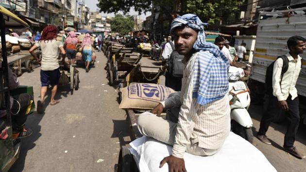 Hauling sacks more than double their weight amidst the dust and sweltering heat of Old Delhi, these daily wage earners toil day and night ensuring the working of the grain markets using hand carts or ‘thelas’ to transport goods by loading and unloading in the narrow bylanes of the historical city. (Burhaan Kinu/HT PHO )