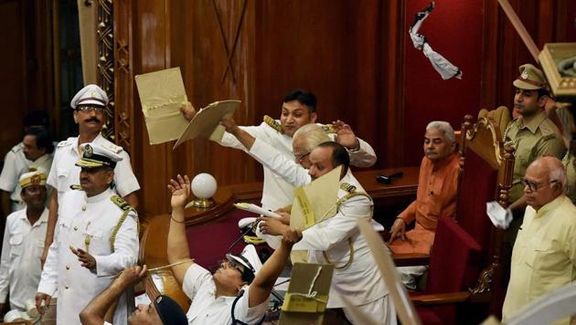 Marshals protect UP Governor Ram Naik from paper balls thrown by agitating Opposition MLAs during his address on the first day of the UP Assembly session in Lucknow on Monday.(PTI Photo)