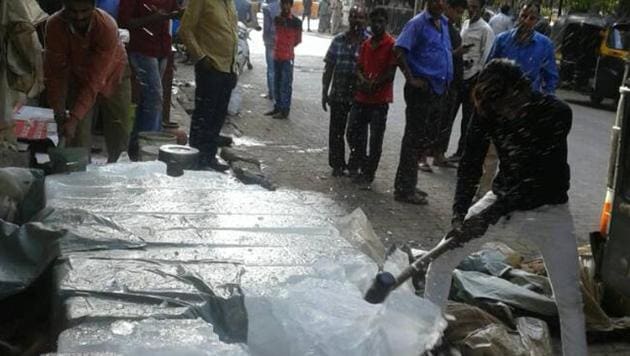 A civic worker destroys blocks of contaminated ice in Mumbai. (HT) A civic worker destroys blocks of contaminated ice in Mumbai. (HT)