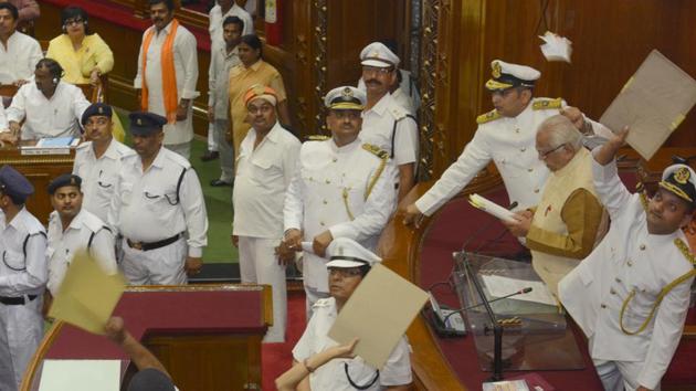Marshals deflecting paper balls thrown by opposition members at governor Ram Naik on the first day of the state assembly session in Lucknow on Monday. (Ashok Dutta/HT Photo)