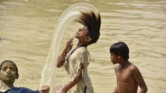 Children cool off at a water tank in Noida. (Virendra Singh Gosain/HT PHOTO)