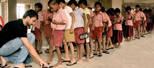 Shriyans Bhandari distributing slippers to underprivileged children . Shriyans Bhandari distributing slippers to underprivileged children .