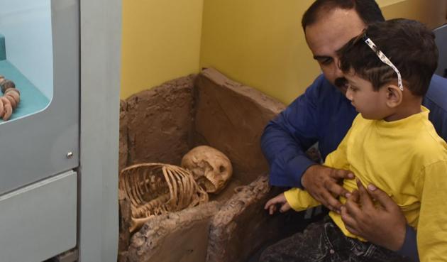 Arnav Desai, 4, checks out a Megalithic Age burial setup, amid some calming reassurance from his dad. His mother took the day off from work so the family could make it to the ‘bus museum’, which was parked at the Phoenix Mill mall on Thursday.(Anshuman Poyrekar / HT Photo)