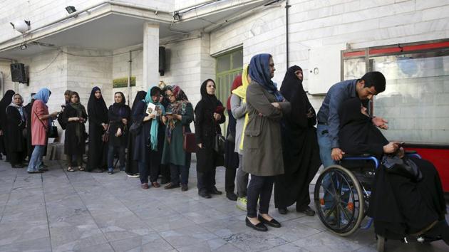 Iranian voters queue at a polling station for the presidential and municipal council election in Tehran on Friday.(AP)