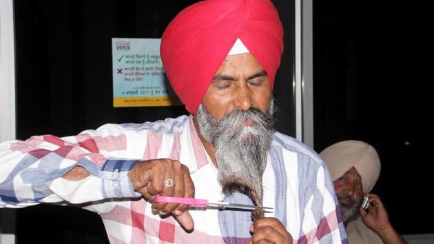 Bahona village sarpanch Harbhajan Singh cutting his beard outside the DC office in Moga on Friday, May 19.(HT Photo)