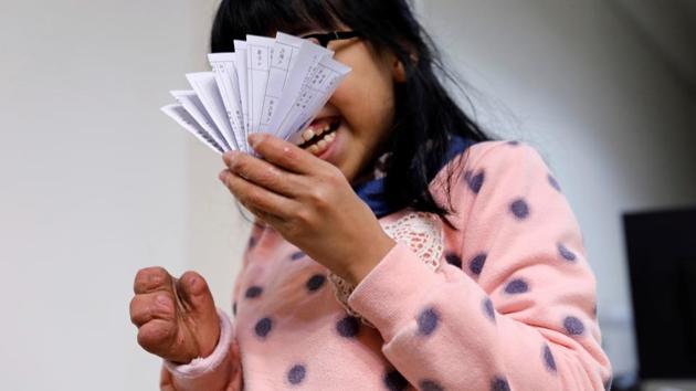 A girl who injured her hand in a scalding accident when she was nine months old, reacts as she holds papers in Taoyuan, Taiwan.Conventional prosthetic limb wearers often experience prosthetic socket discomfort compared to the far superior and comfortable 3D printed prosthetics. (Tyrone Siu /REUTERS)