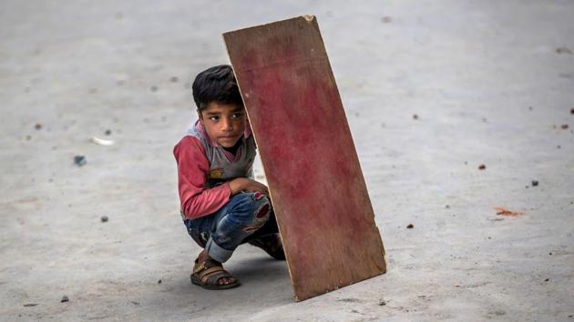 A Kashmiri boy shields himself with plywood from stones and glass marbles during a clash between Indian policemen and protesters during a protest in Srinagar, Indian controlled Kashmir. (Dar Yasin/AP)