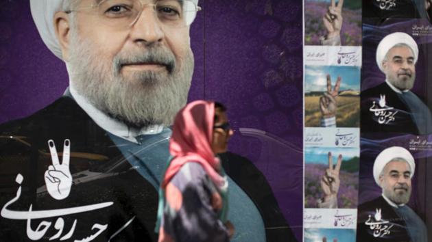 An Iranian woman walks past portraits of President Hassan Rouhani outside his campaign headquarters in Tehran on May 20, 2017. Rouhani secured a convincing election victory with voters backing his efforts to rebuild foreign ties, as initial results were announced.(AFP Photo)