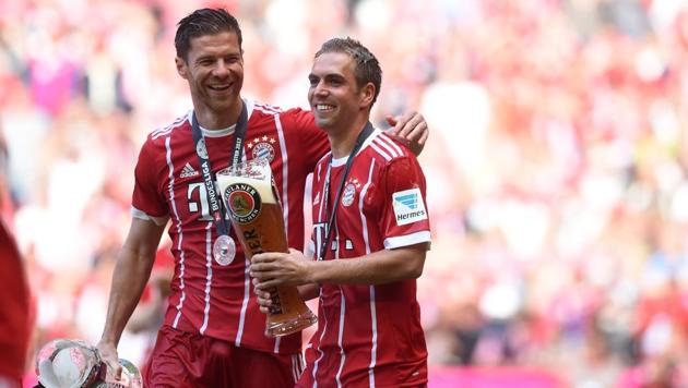 Bayern Munich players Philipp Lahm (R) and Xabi Alonso (L) celebrate with beer after their Bundesliga match against SC Freiburg in Munich.(AFP)