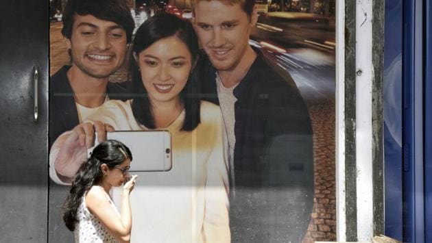 A girl walks past the mobile phone advertisement at Elphinstone road in Mumbai, India. (Pratik Chorge/HT Photo)
