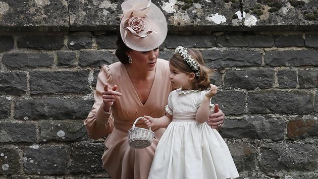 Britain's Catherine, Duchess of Cambridge (L) speaks to her daughter Britain's princess Charlotte, a bridesmaid, following the wedding . (KIRSTY WIGGLESWORTH / AFP) 