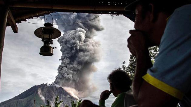 Villagers look on as Mount Sinabung volcano spews thick volcanic ash, as seen from Beganding village in Karo, North Sumatra province. Sinabung roared back to life in 2010 for the first time in 400 years. After another period of inactivity, it erupted once more in 2013 and has remained highly active since. (Ivan DAMANIK / AFP)