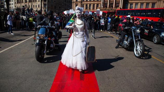 A woman dressed in a wedding gown and holding a South African flag leads a march organized on May 20, 2017 in Pretoria against the abuse of women following the spike in reports of women being murdered and raped in various parts of the country. Hundreds of people gathered to march from Church Square to the Union Buildings in Pretoria, South Africa. The march was themed: ‘Not In My Name’. (WIKUS DE WET / AFP)