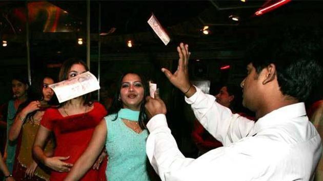 Money rains down on performers in bright red and blue dress in a Kolkata bar.(Picture courtesy: Rajeev Sarkar)