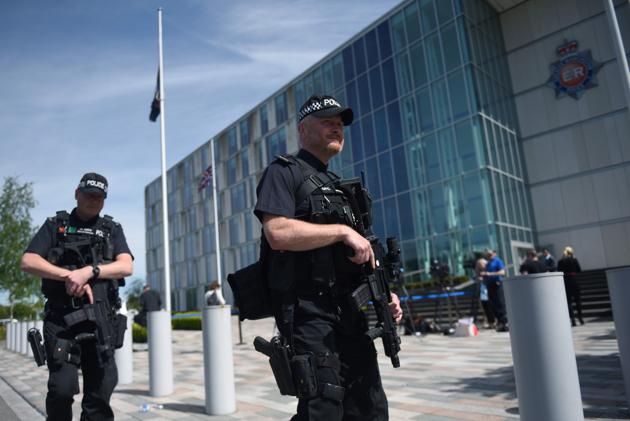 Flags fly at half-mast as armed British Police officers walk on patrol with their weapons outside of Greater Manchester Police force's headquarters in Manchester, during a visit by Britain's Prime Minister Theresa May. (Oli SCARFF/AFP Photo)