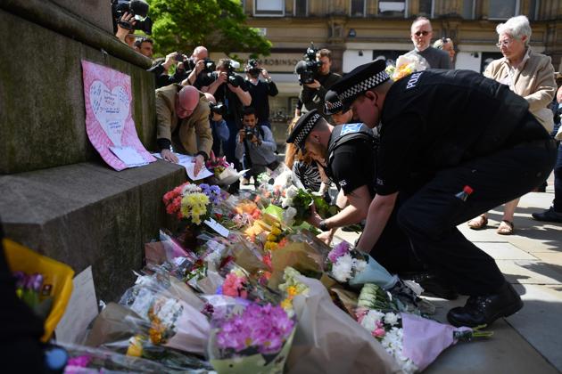 Police officers relocate floral tributes in St Ann's Square in Manchester, northwest England, laid as a mark of respect to those in killed and injured at the Manchester Arena. (Ben STANSALL/AFP Photo)