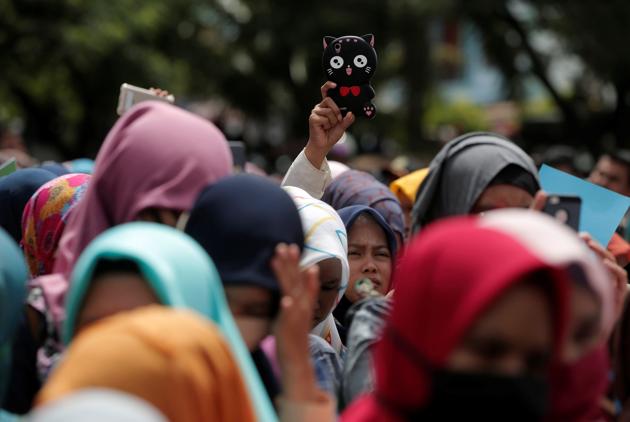 Indonesian women hold smartphones as they watch a man publicly caned for having gay sex. (REUTERS)