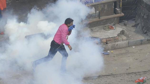 A BJP activist protects himself as he tries to evade a tear gas attack from the police. (Samir Jana/HT PHOTO) 