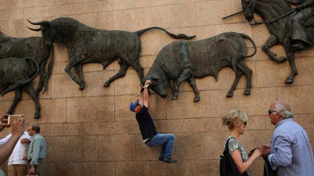 A man has his photo taken hanging from a bull sculpture outside Las Ventas bullring in Madrid. (Susana Vera / REUTERS) A man has his photo taken hanging from a bull sculpture outside Las Ventas bullring in Madrid. (Susana Vera / REUTERS)