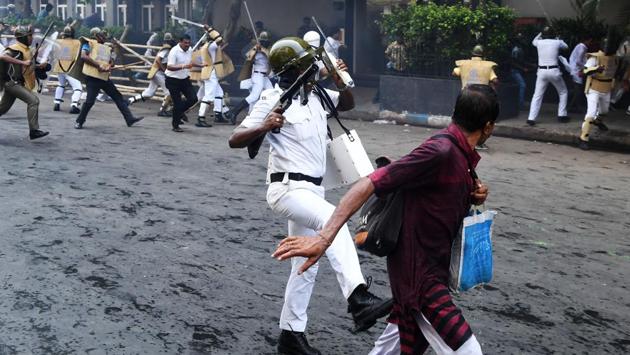 A policeman charges at activists of the Bhartiya Janata Party (BJP)  in Kolkata .  (Dibyangshu  Sarkar/AFP) 