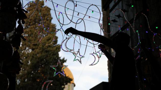 A Palestinian man hangs decorations at the entrance to the compound. (Ammar Awad/REUTERS)