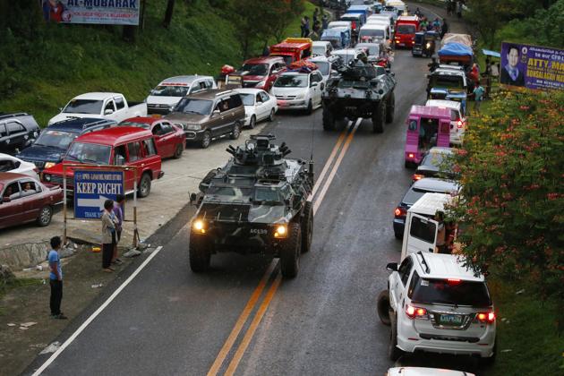 Armoured cars make their way through a queue of vehicles with fleeing residents as Muslim militants lay siege in Marawi city. (AP) Armoured cars make their way through a queue of vehicles with fleeing residents as Muslim militants lay siege in Marawi city. (AP)