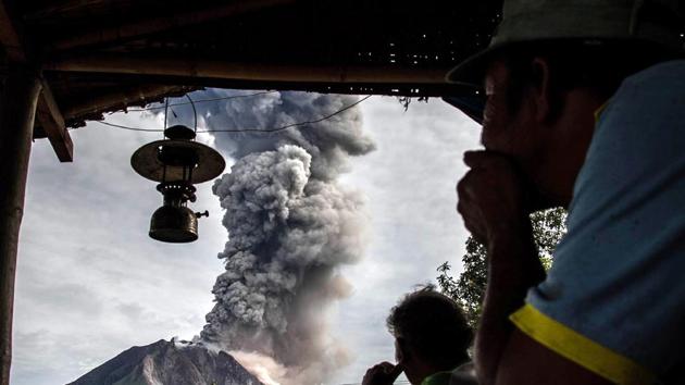 Villagers look on as Mount Sinabung volcano spews thick volcanic ash, as seen from Beganding village . (Ivan DAMANIK / AFP)
