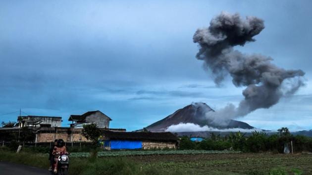 Motorists ride along a road as Mount Sinabung volcano spews thick volcanic ash . Three years on and the mountain is still emitting out clouds of steam and dust. (TIBTA PANGIN / AFP)