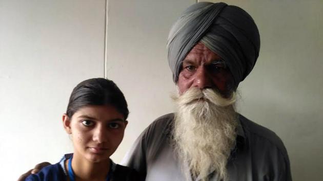 Manpreet Kaur, topper of Punjab’s Sangrur district in PSEB class-10 examination with her father Bhagwan Singh, a daily wage labourer. (HT PHOTO)